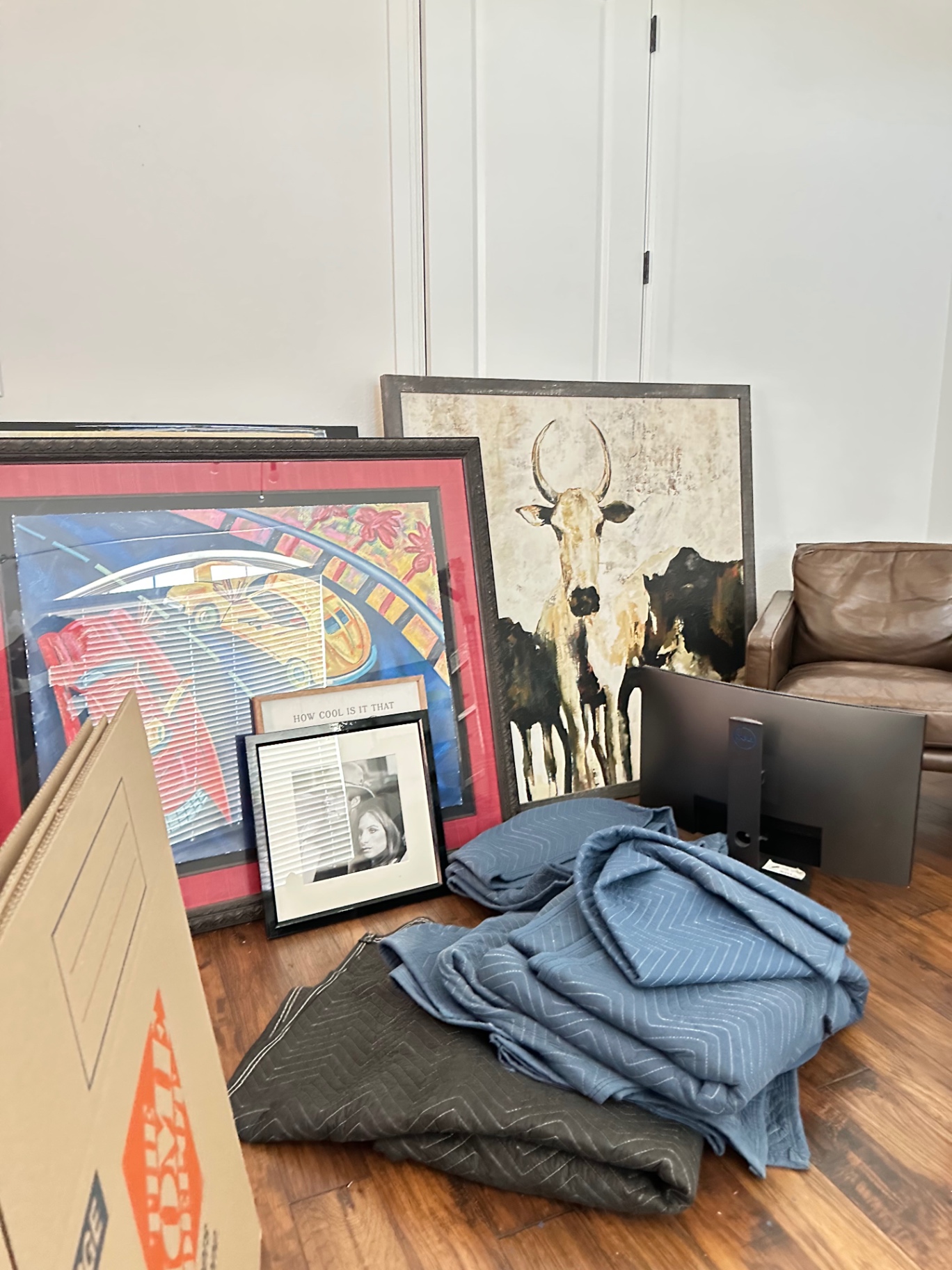 Framed artwork, canvases, and folded moving blankets staged and padded for a specialty move