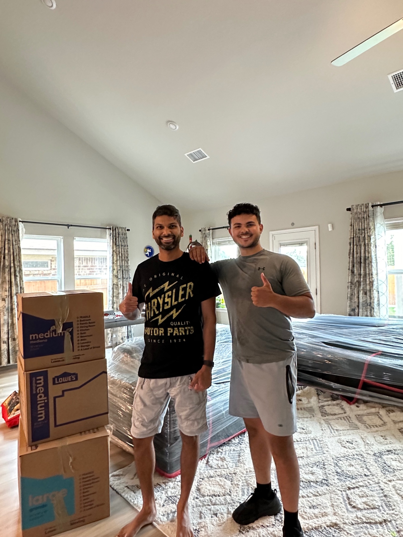 Happy customer and Lovable Moving crew member giving thumbs up next to packed boxes and wrapped furniture