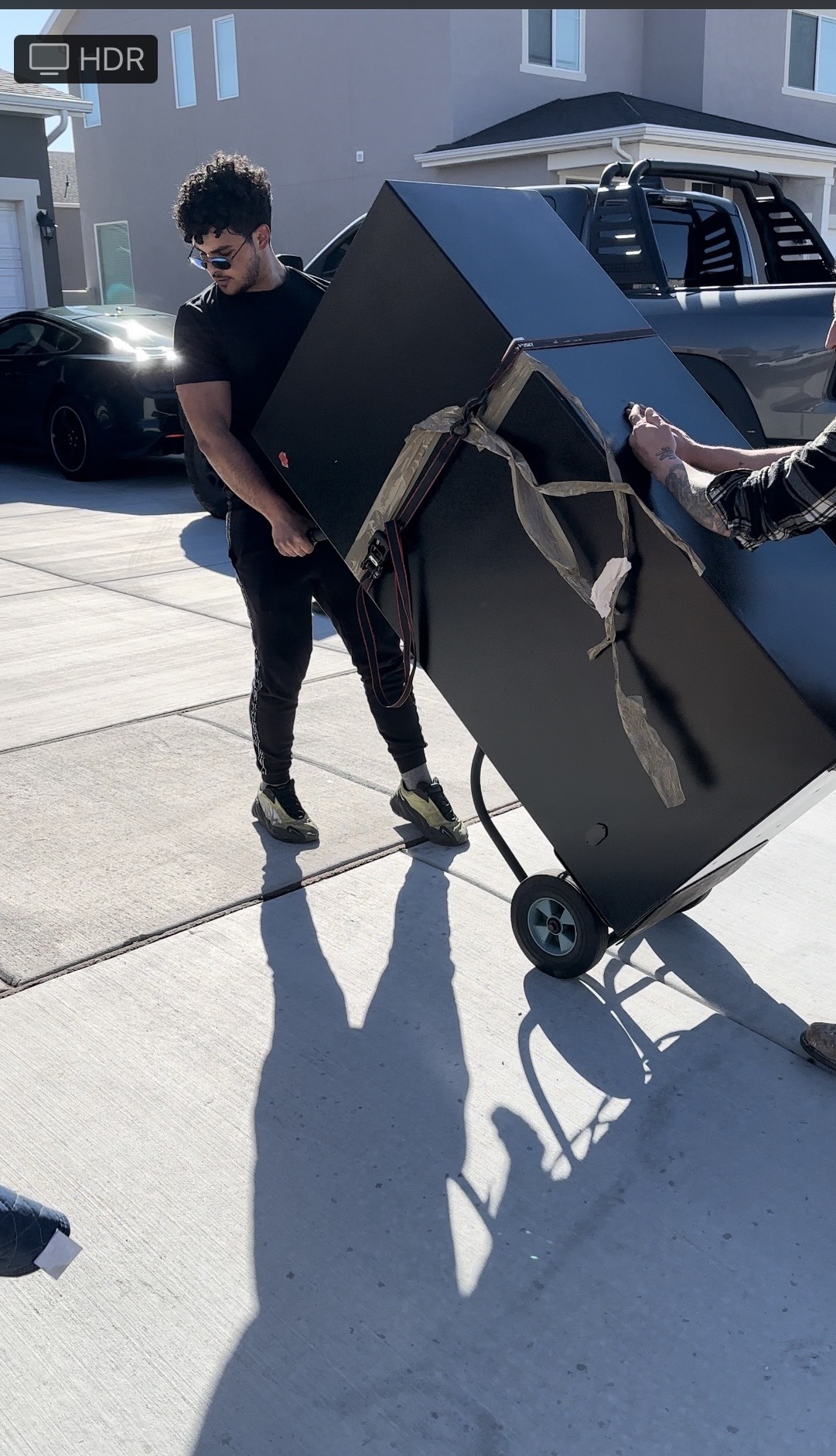 Lovable Moving crew member using a hand truck to carefully wheel a large safe out of an Austin home